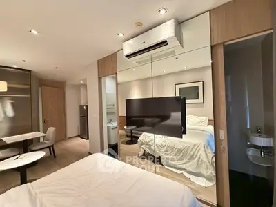 Modern bedroom with mirrored closet and wall-mounted TV in stylish apartment
