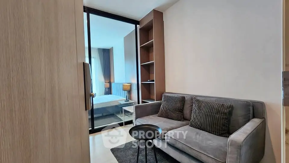 Modern living room with cozy sofa and view into stylish bedroom