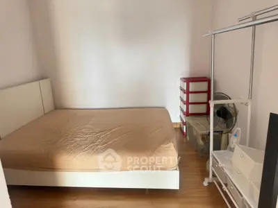 Cozy minimalist bedroom with wooden flooring and simple storage solutions.