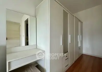 Spacious bedroom with modern white wardrobe and vanity, featuring sleek design and ample storage space.