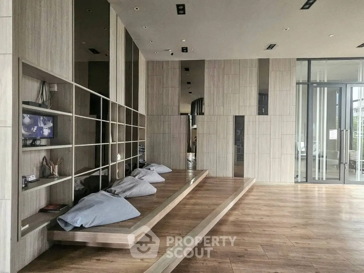 Modern communal area with wooden flooring and cozy seating in a stylish building.