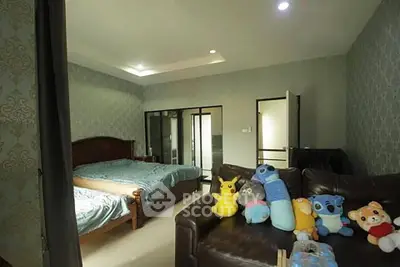 Spacious bedroom with elegant decor and plush toys on a leather sofa, perfect for family living.