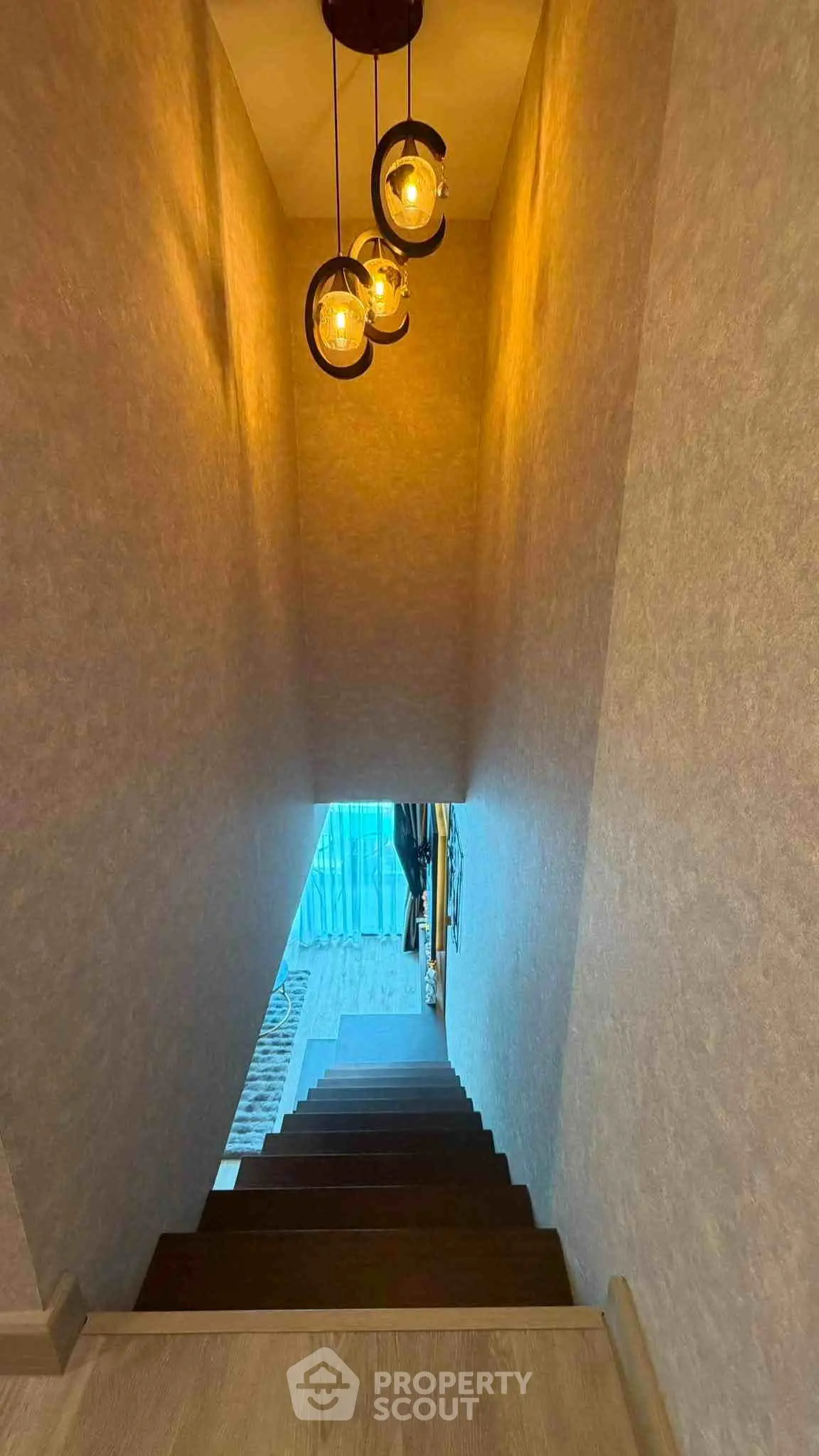 Elegant staircase with modern lighting leading to a bright lower level, showcasing stylish interior design.