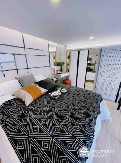 Modern bedroom with stylish decor and geometric patterned bedding in a contemporary apartment.