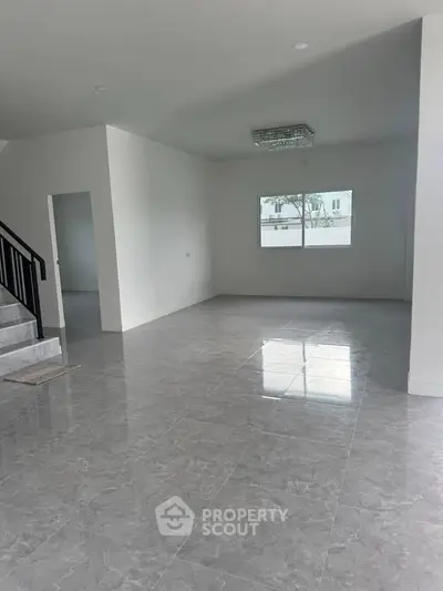 Spacious modern living room with elegant tile flooring and large window for natural light.