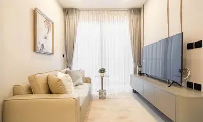 Modern living room with sleek furniture and large TV, featuring elegant curtains and cozy ambiance.