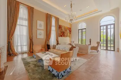 Luxurious living room with high ceilings, elegant chandelier, and large windows offering abundant natural light.