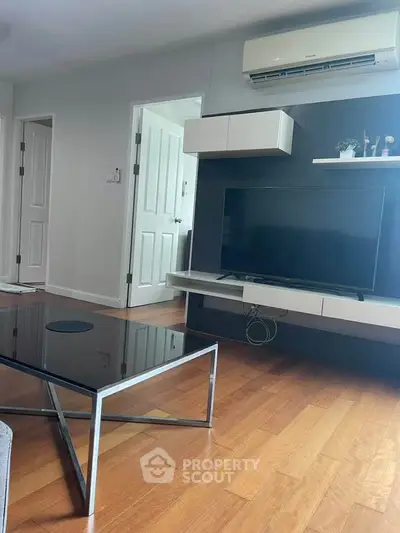 Modern living room with sleek TV unit and air conditioning, featuring stylish wooden flooring.