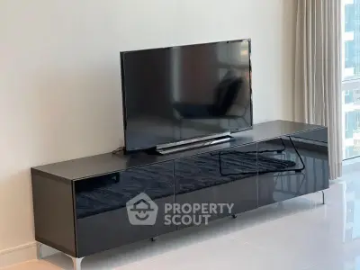 Modern living room with sleek black TV stand and large flat-screen TV, perfect for entertainment.