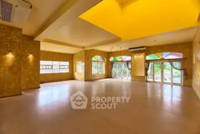 Spacious living room with vibrant yellow walls and large windows offering natural light.