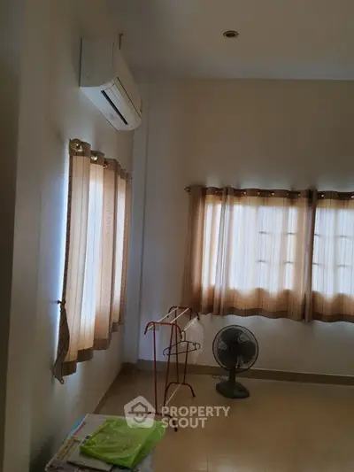 Spacious and well-lit living space with air conditioning, large windows draped with elegant curtains, and tiled flooring, perfect for comfortable urban living.