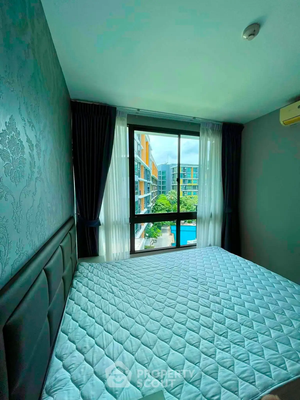 Modern bedroom with large window offering a stunning view of the pool and surrounding buildings.