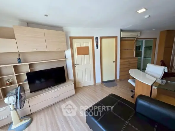 Modern living room with sleek furniture and TV, featuring light wood accents and ample storage space.