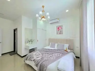 Luxurious bedroom with elegant chandelier and plush bedding in modern apartment.