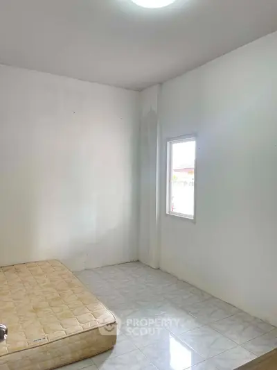 Minimalist bedroom with mattress and natural light from window