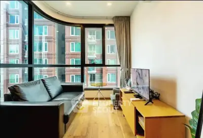 Modern living room with large windows and city view, featuring sleek furniture and wooden flooring.