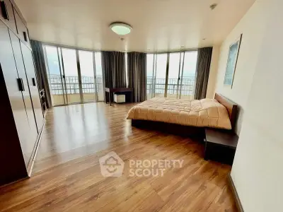 Spacious bedroom with large windows and wooden flooring, offering stunning views and ample natural light.