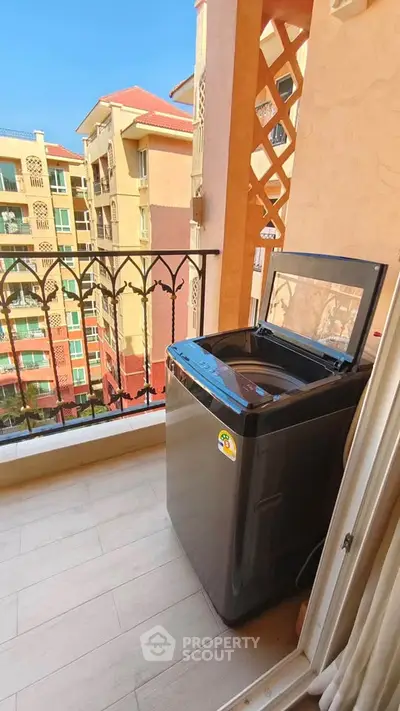 Charming balcony with washing machine and scenic view of colorful buildings.