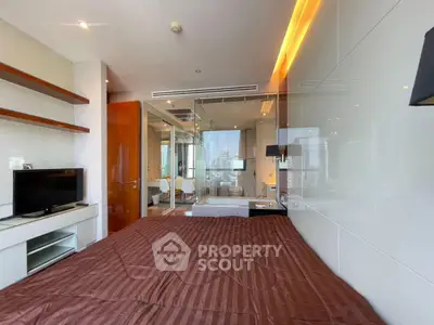 Luxurious bedroom with modern glass-walled bathroom and city view, featuring sleek design and ambient lighting.