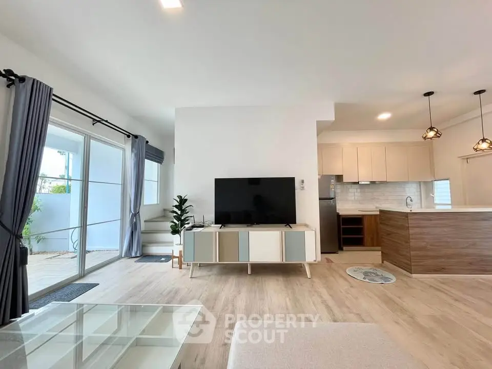 Spacious modern living room with open kitchen and large windows for natural light.
