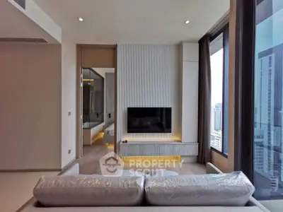 Modern living room with large windows and city view, featuring sleek TV setup and cozy sofa.