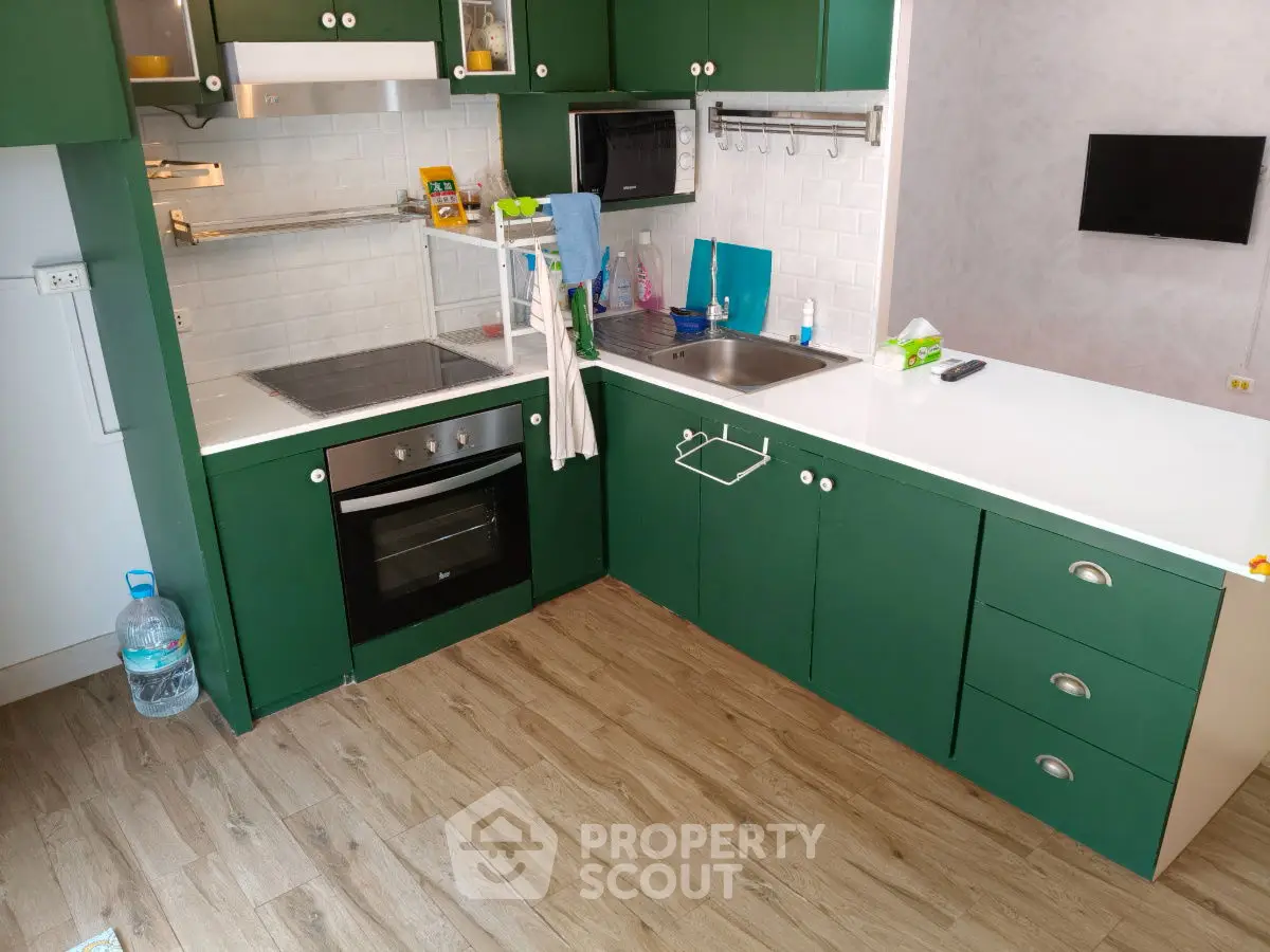Modern kitchen with green cabinets, oven, and sleek countertops