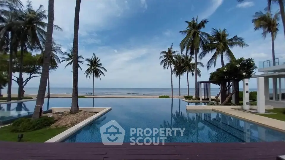 Luxurious beachfront pool with stunning ocean view and palm trees, perfect for relaxation and leisure.