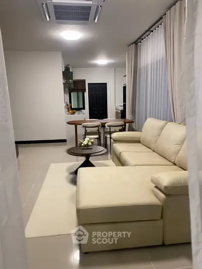 Modern living room with beige sectional sofa and elegant decor in open layout apartment.