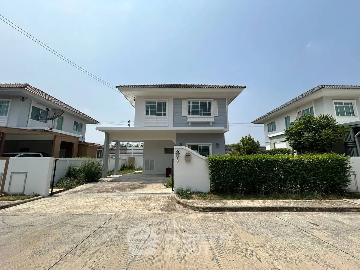 Charming two-story white house with manicured hedges and spacious driveway in a serene neighborhood.