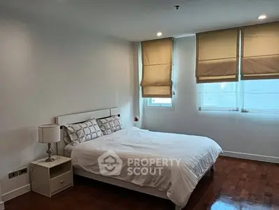 Spacious bedroom with large windows and elegant wooden flooring in modern apartment.