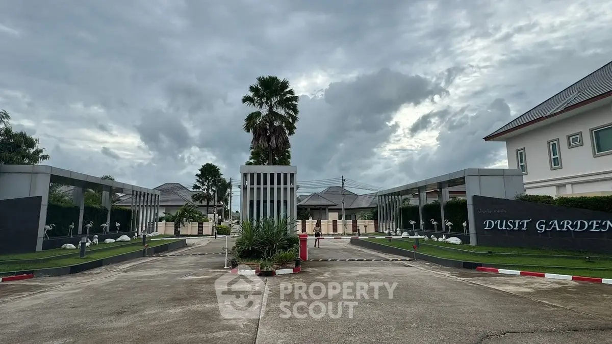 Elegant entrance of Dusit Garden estate with modern architecture and lush greenery.