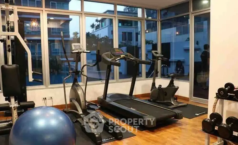 Modern gym with cardio equipment and large windows in upscale building