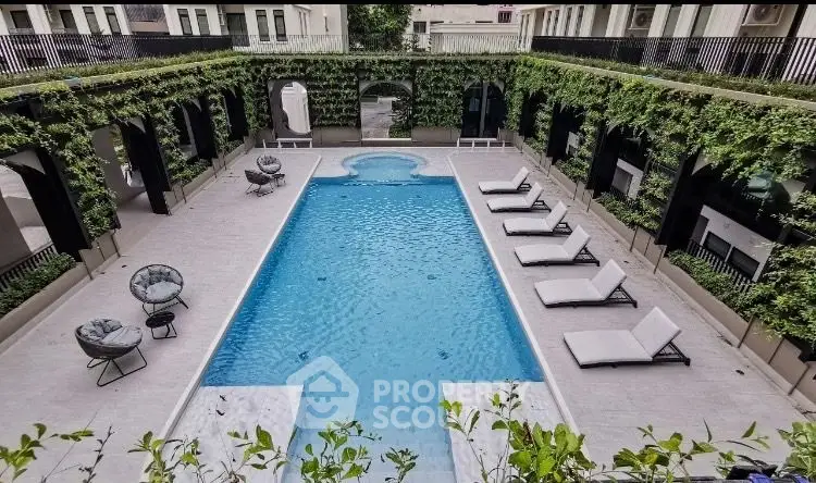 Luxurious outdoor pool with elegant loungers and lush greenery