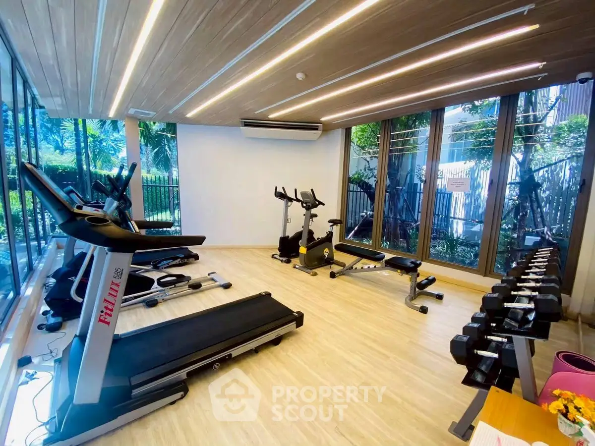 Modern gym with state-of-the-art equipment and large windows offering garden views.