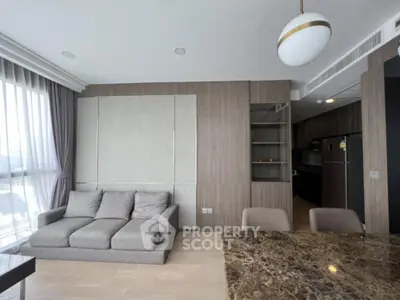 Modern living room with stylish decor and open kitchen layout, featuring a cozy sofa and elegant dining area.