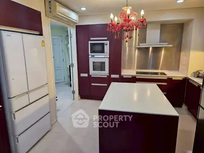 Modern kitchen with island, red cabinetry, and chandelier lighting
