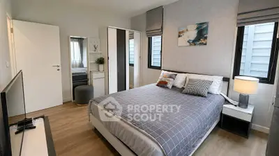 Modern bedroom with stylish decor and ample natural light, featuring a comfortable bed and sleek furnishings.