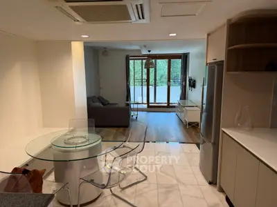 Modern open-plan living room with glass dining table and balcony view.