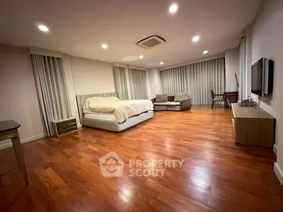 Spacious bedroom with hardwood floors and modern furnishings