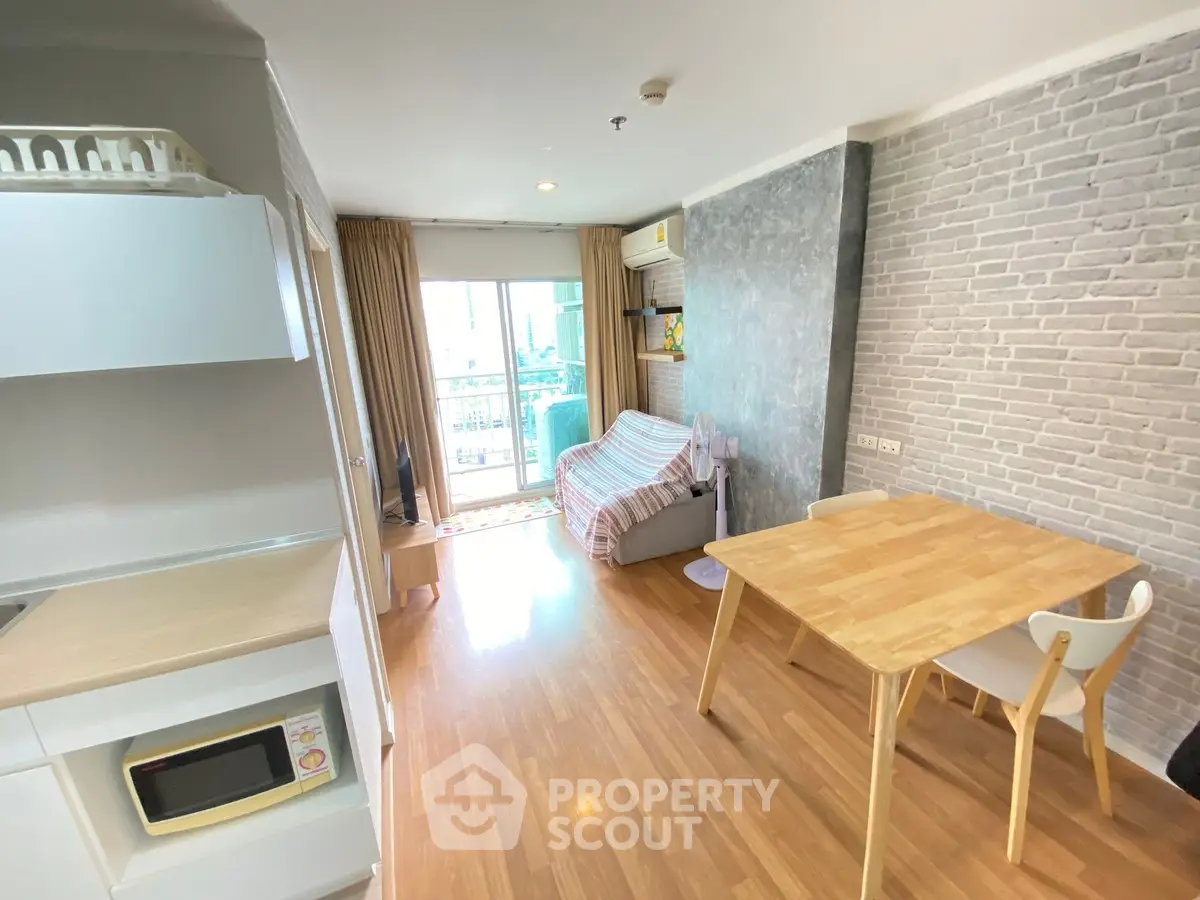 Modern living room with wooden flooring and balcony access in a cozy apartment.