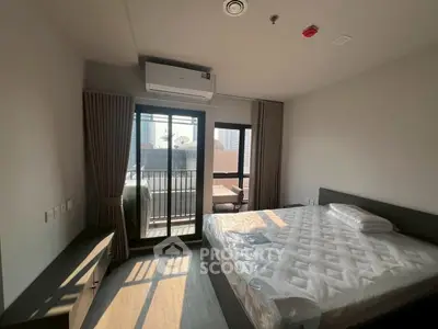 Modern bedroom with balcony access and city view, featuring a comfortable bed and air conditioning.
