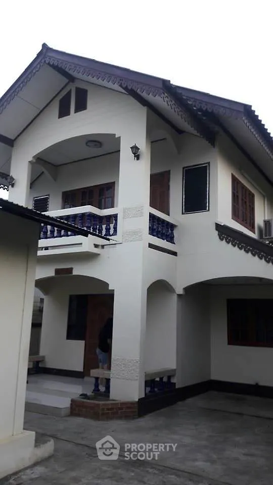 Charming two-story home with traditional design, featuring a spacious balcony with intricate railings, large windows, and a welcoming entrance.