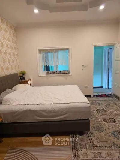 Spacious bedroom with elegant decor and cozy ambiance, featuring a comfortable bed and stylish wallpaper.