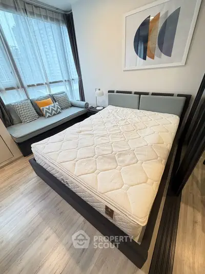 Modern bedroom with stylish decor and large window view in urban apartment.
