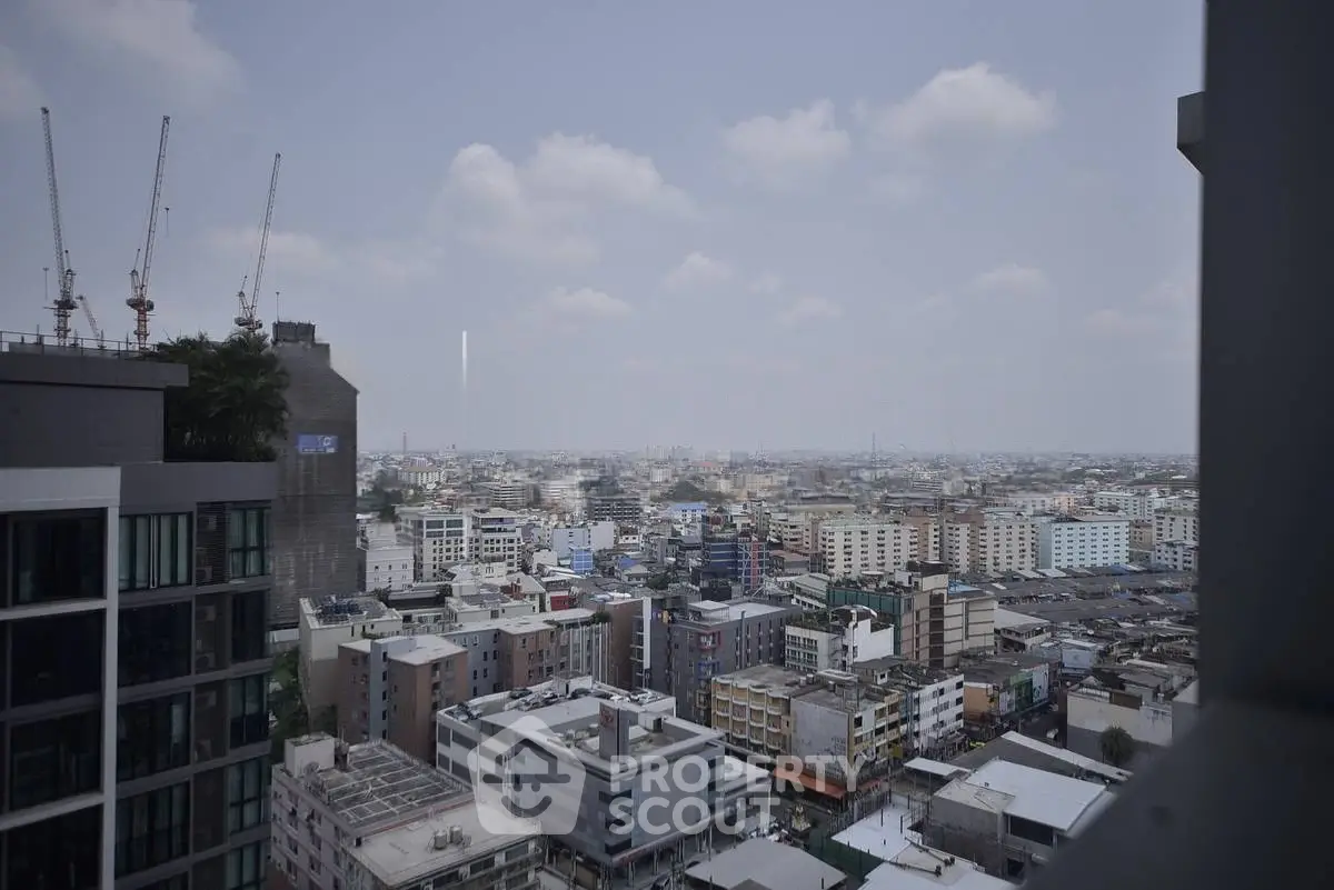 Stunning cityscape view from high-rise building showcasing urban skyline and construction cranes.