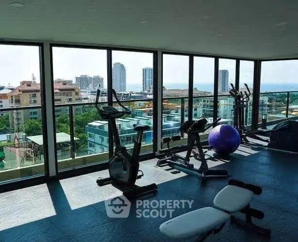 Spacious gym with panoramic city views and modern fitness equipment.