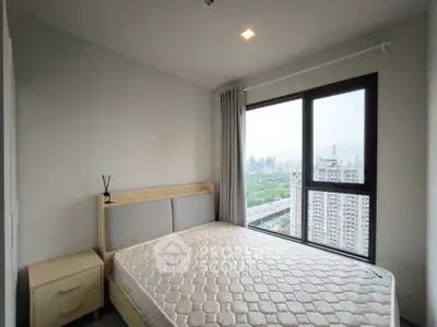 Modern bedroom with large window offering stunning city view in high-rise apartment.