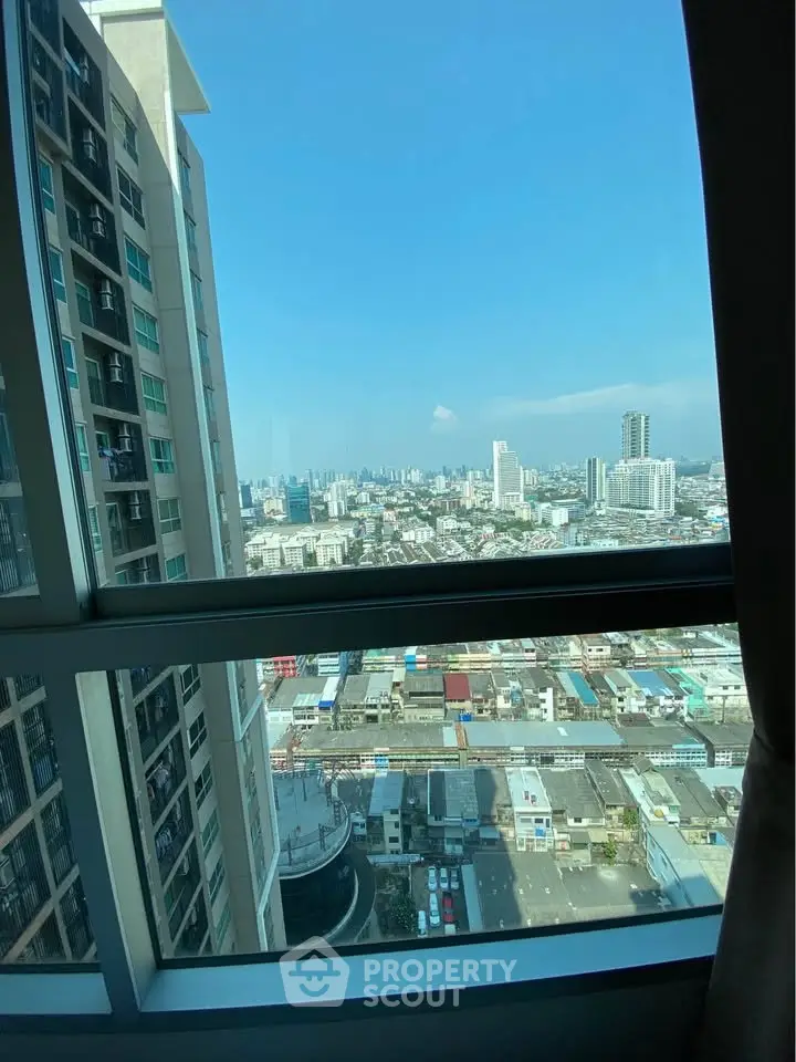 Stunning cityscape view from high-rise apartment window, showcasing urban skyline and clear blue sky.
