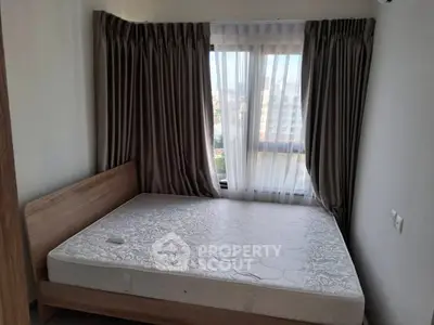 Cozy bedroom with large window and elegant curtains, featuring a comfortable bed and natural light.