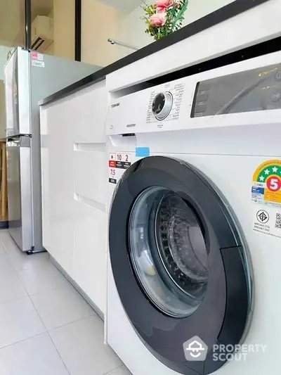 Modern kitchen with washing machine and fridge in sleek design